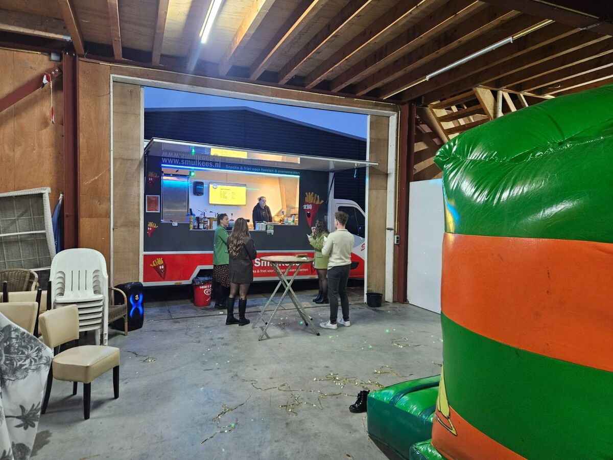 Smulkees frietwagen in een loods met feestverlichting