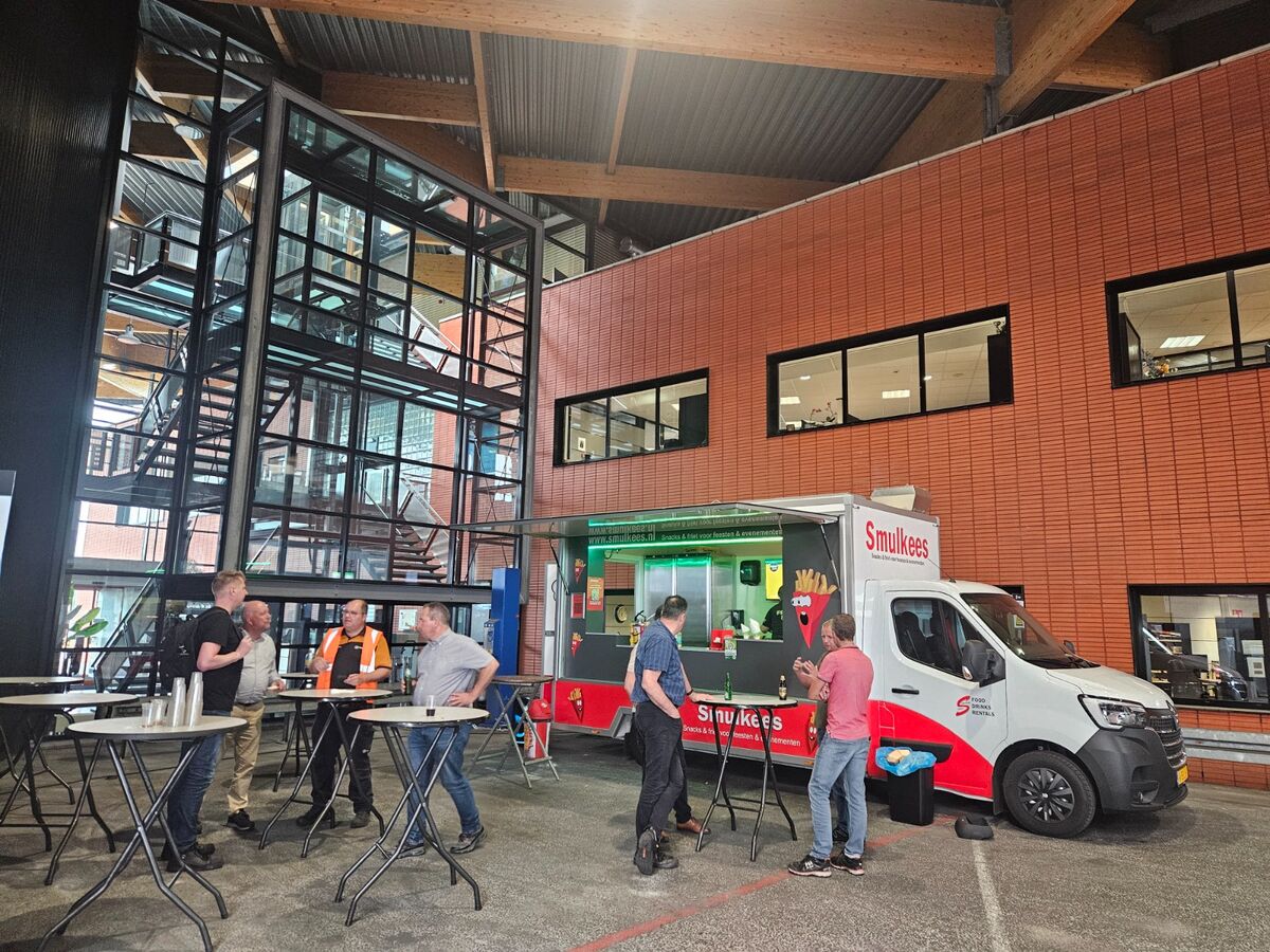 Smulkees frietwagen in een bedrijfshal met statafels