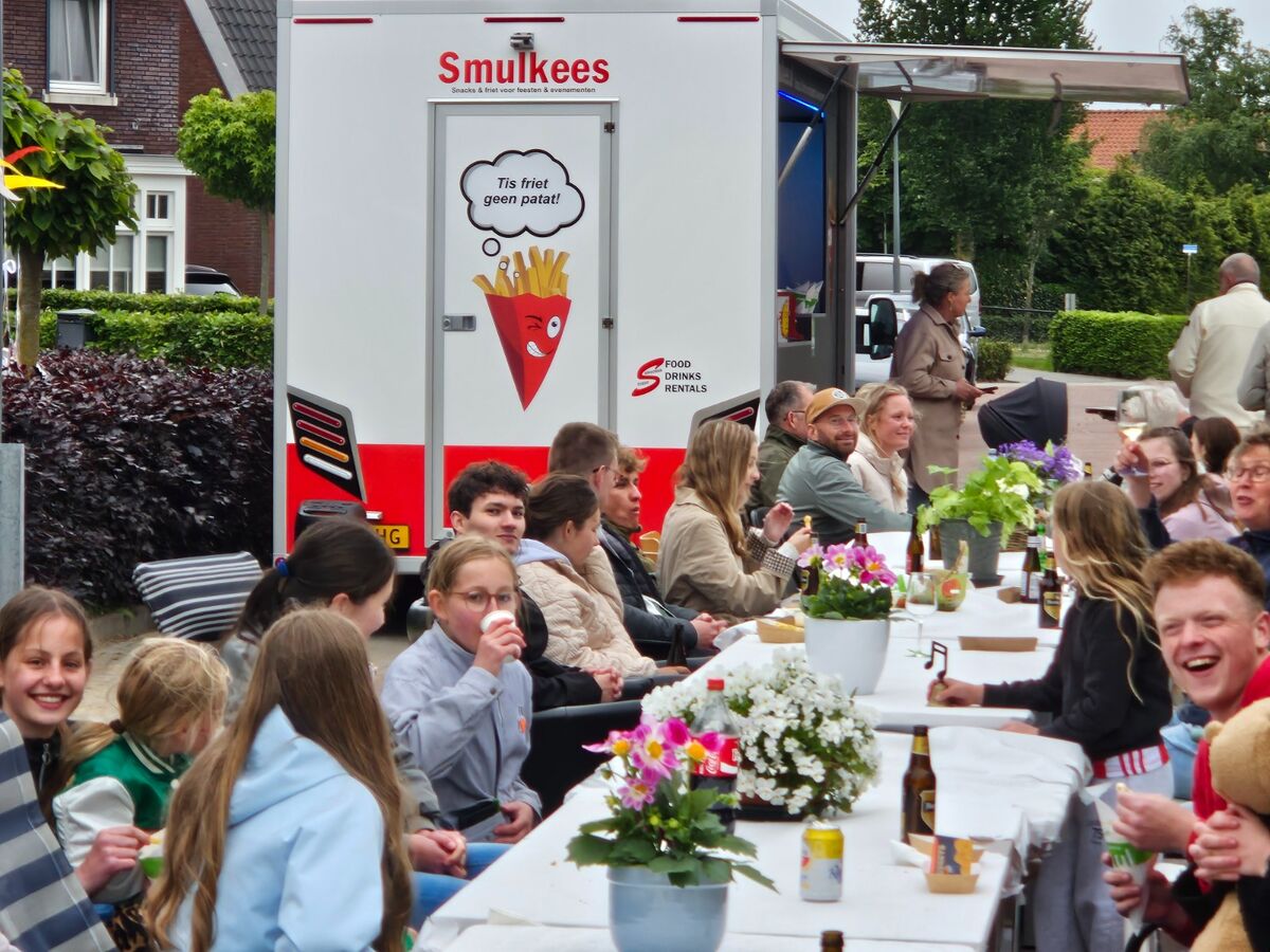 Smulkees frietwagen op een Koningsdag-feest met oranje vlaggen