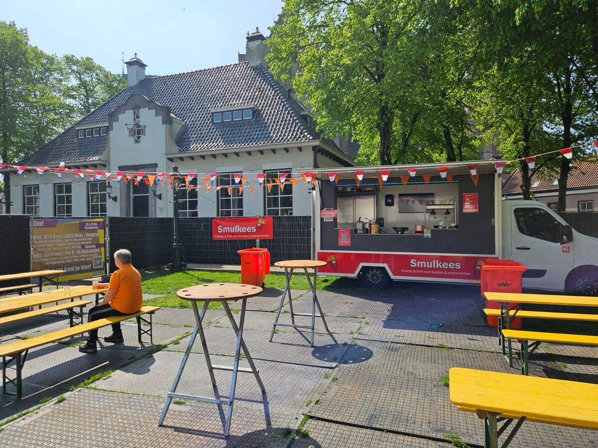 Lange feesttafel met buurtbewoners bij Smulkees frietwagen