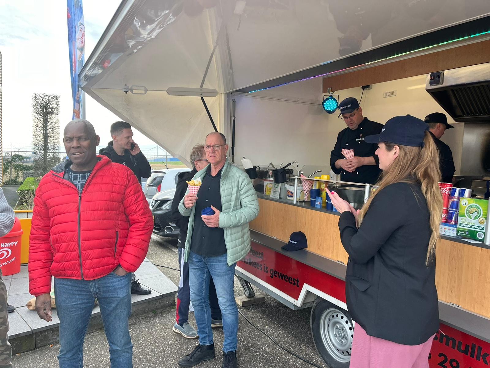 Klanten genieten van verse friet bij de Smulkees wagen